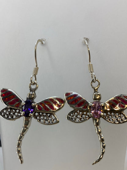 Aretes de ópal de fuego en la mano, 4.5 cm de largo, luz natural acentuando el juego del color