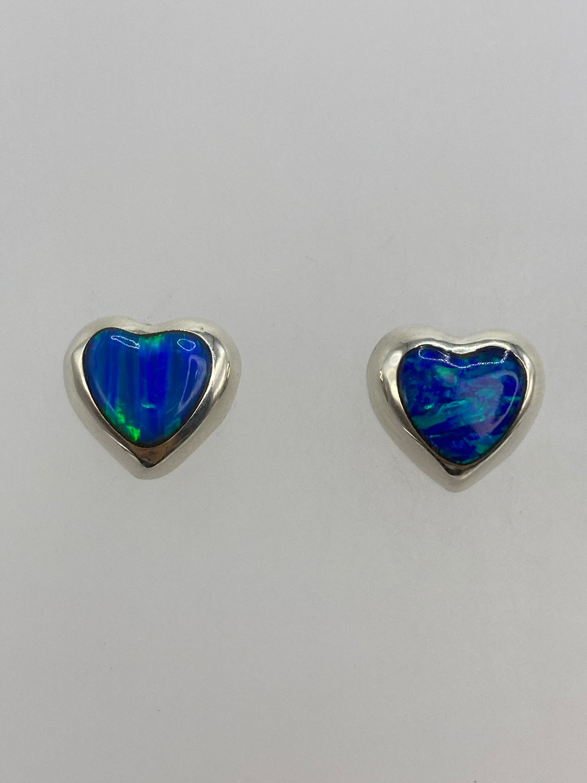 Par de aretes de plata con ópalo de fuego azul en forma de gota, vistos de frente