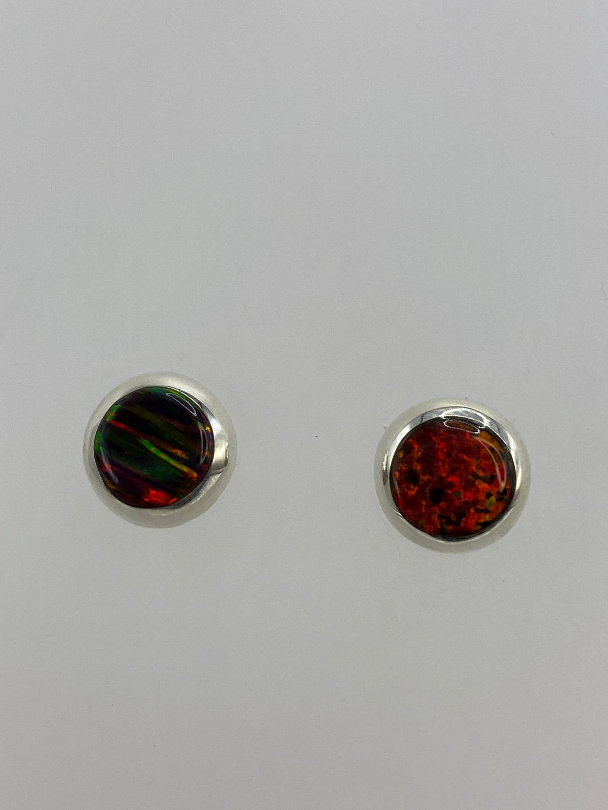 Aretes de plata con Ópalo de Fuego multicolor en mano, mostrando el fuego naranja y rojo