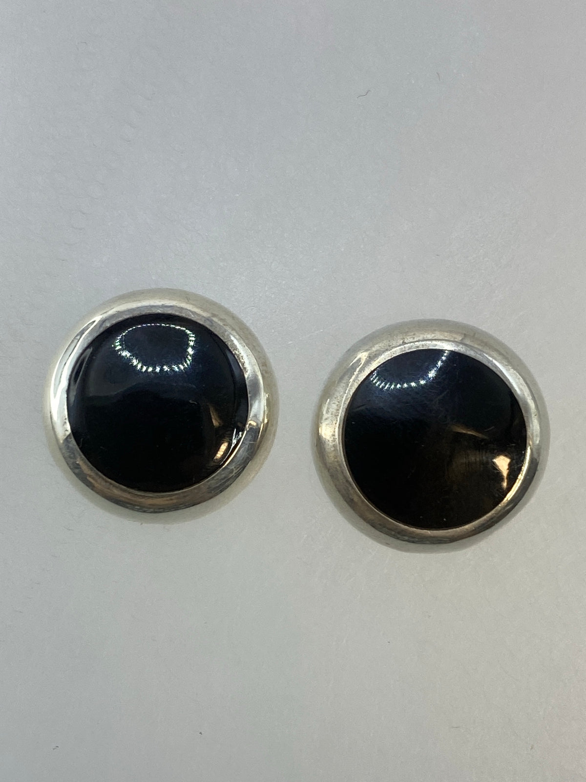 Par de aretes circulares de plata 925 con piedra negra central, vistos de frente