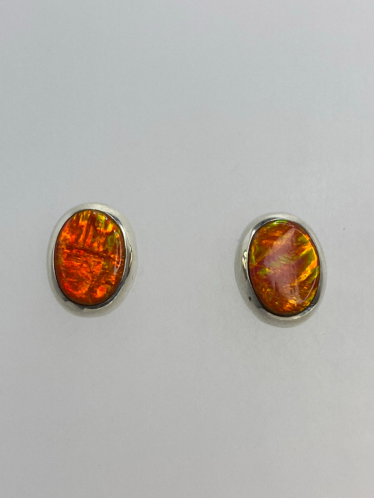 Par de aretes de plata 925 con Opalo de Fuego naranja, frente a fondo gris