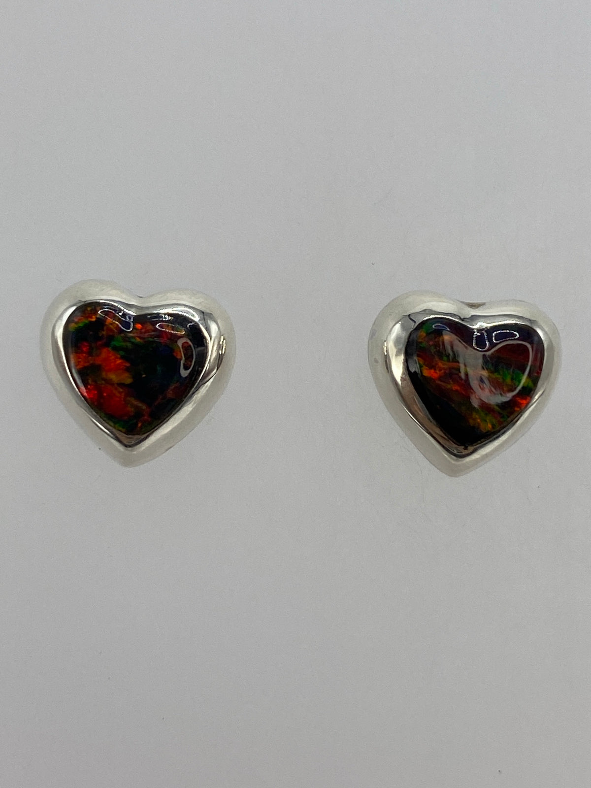 Aretes de ópalo fuego sobre fondo blanco mostrando el Quinto 925