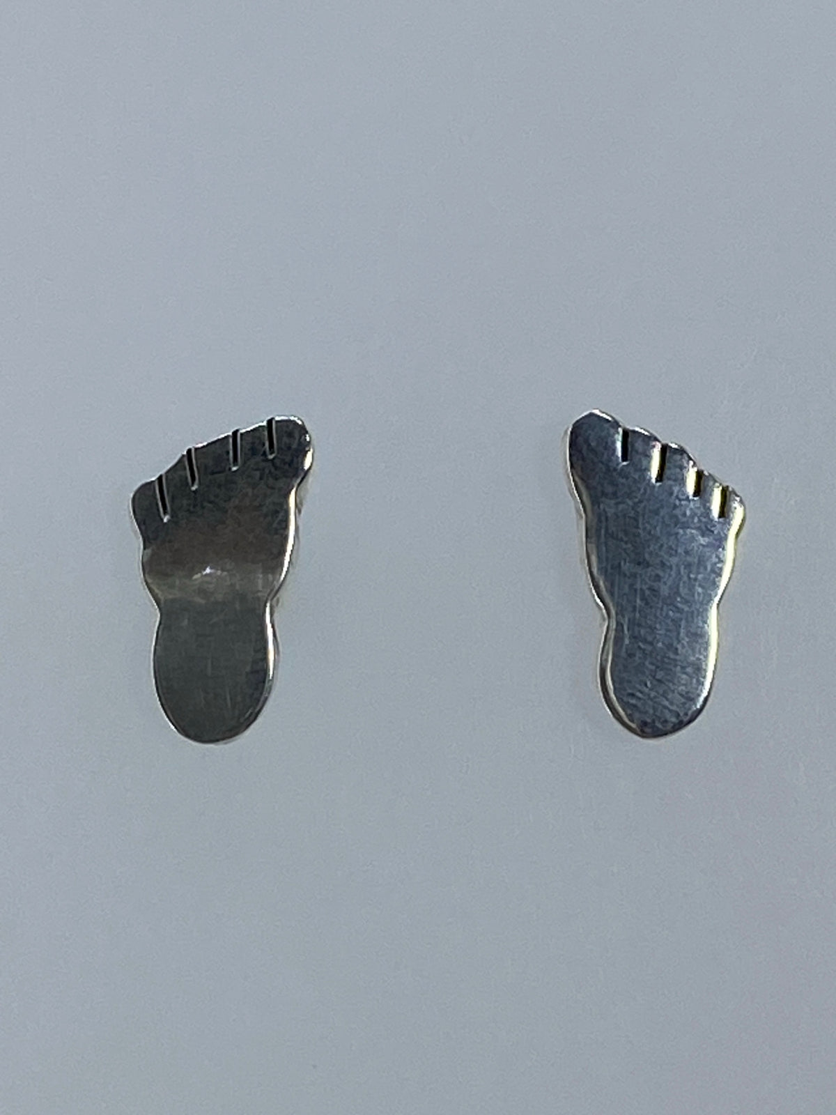 Par de aretes de plata 925 cartoneado, minimalistas, sobre fondo gris