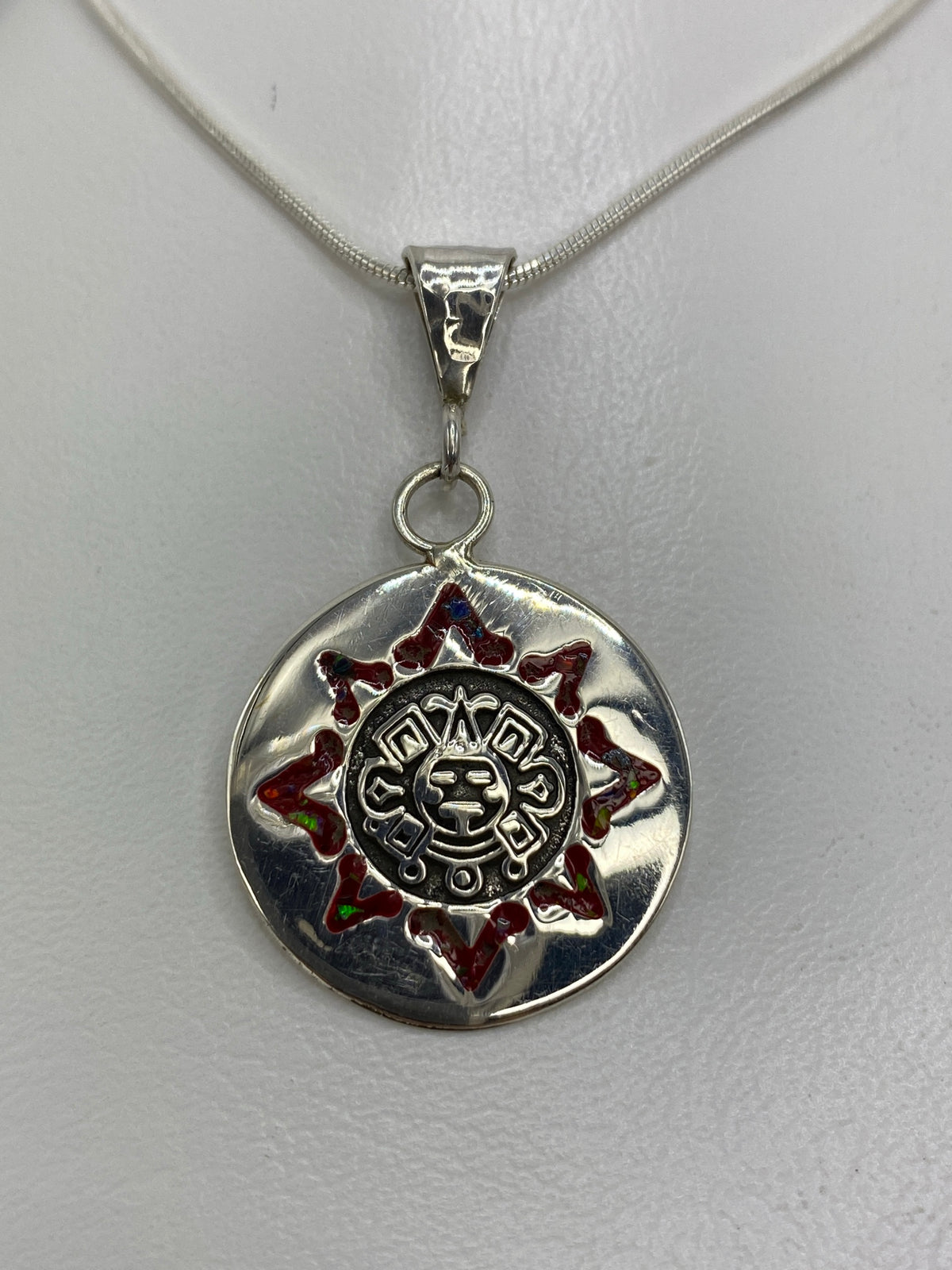 Dije de plata 925 con Calendario Azteca y Ópalo de Fuego rojo en el centro, colgando de cadena de plata