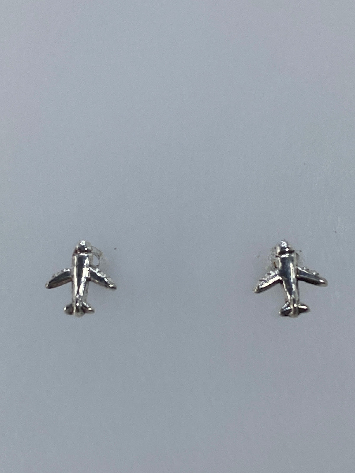 Par de aretes de plata cartoneado minimalista de 1 cm, vistos de frente sobre fondo gris