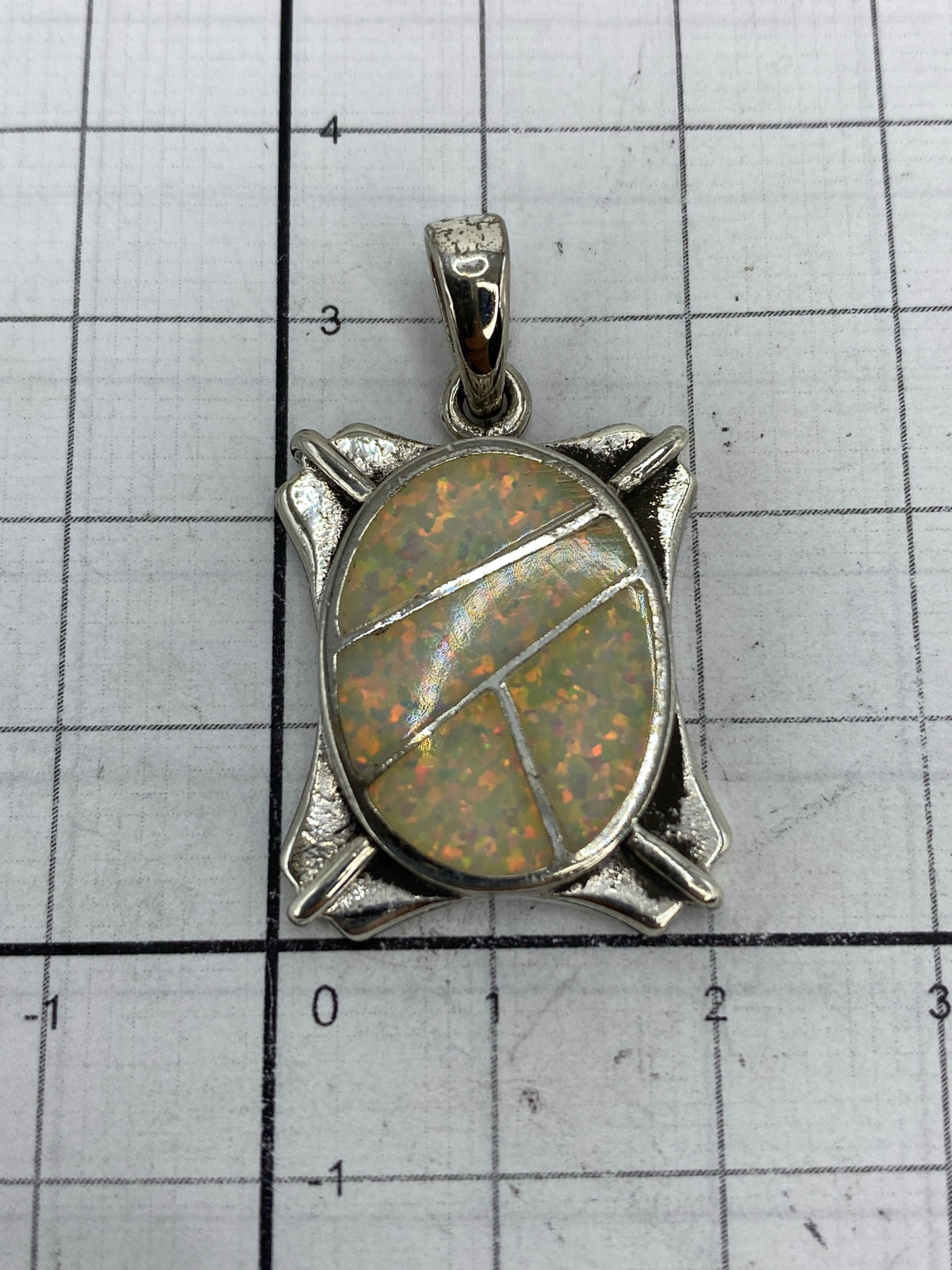 Dije de 3.5 × 2 cm sobre regla — tamaño de pulgar extendido, sin cadena incluida