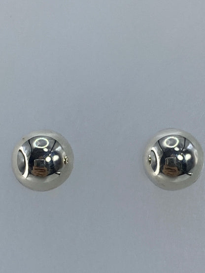 Aretes de plata 1.2 cm sobre fondo blanco mostrando el tamaño minimalista