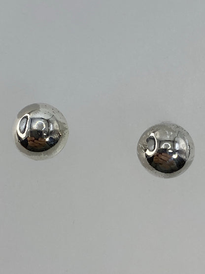 Aretes de bolita de plata sobre fondo blanco mostrando acabado pulido