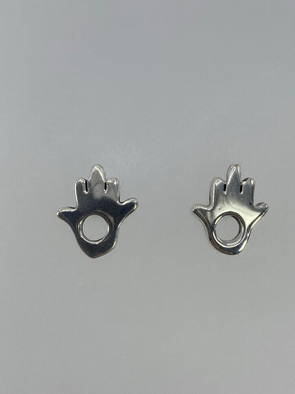 Aretes de plata cartoneado en forma de hamsa con círculo central, vista frontal
