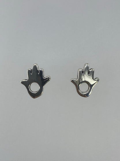 Detalle de los dos aretes de plata hamsa simétricos sobre fondo gris