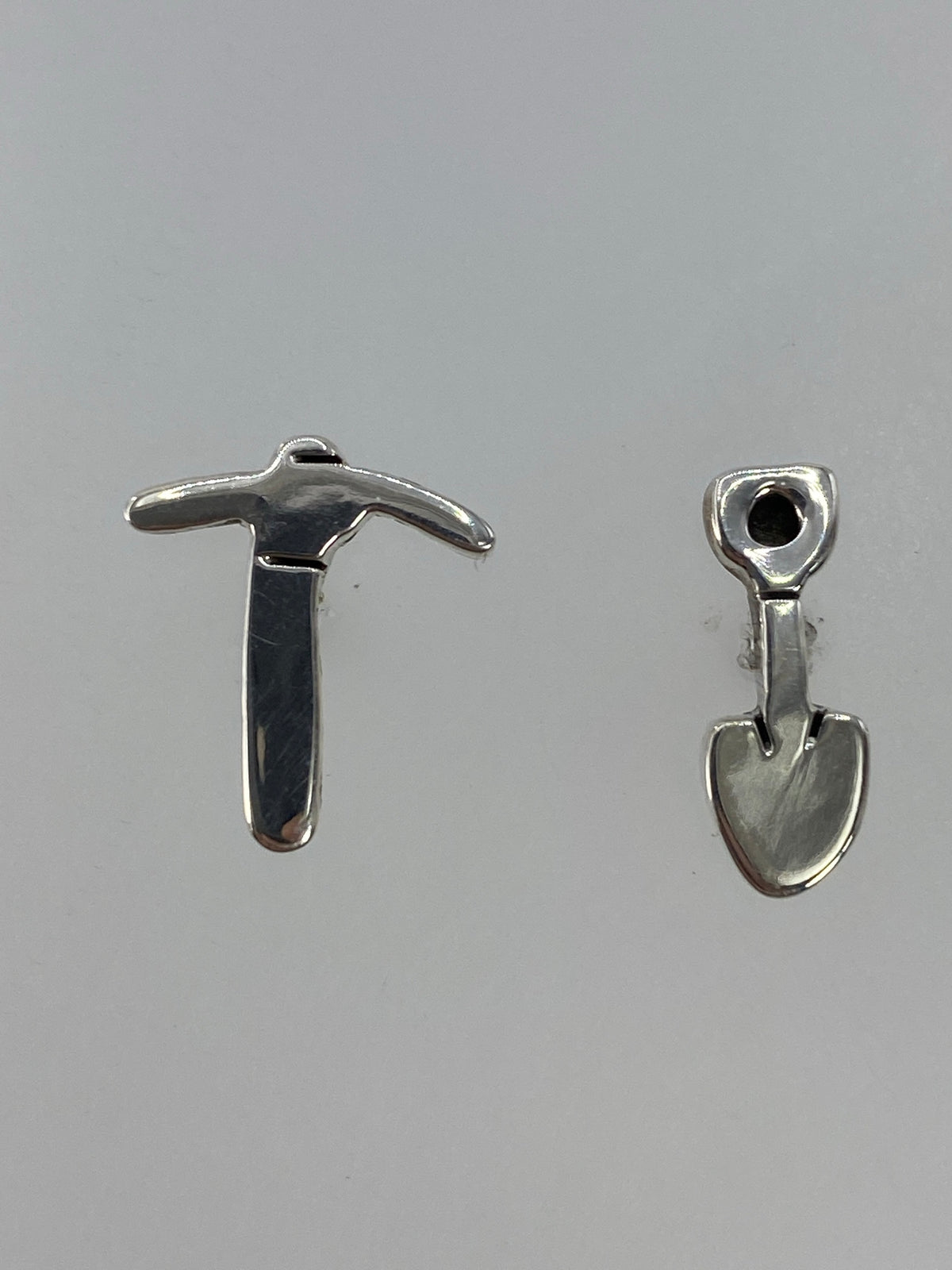 Par de aretes de plata cartoneado en la mano, vista frontal