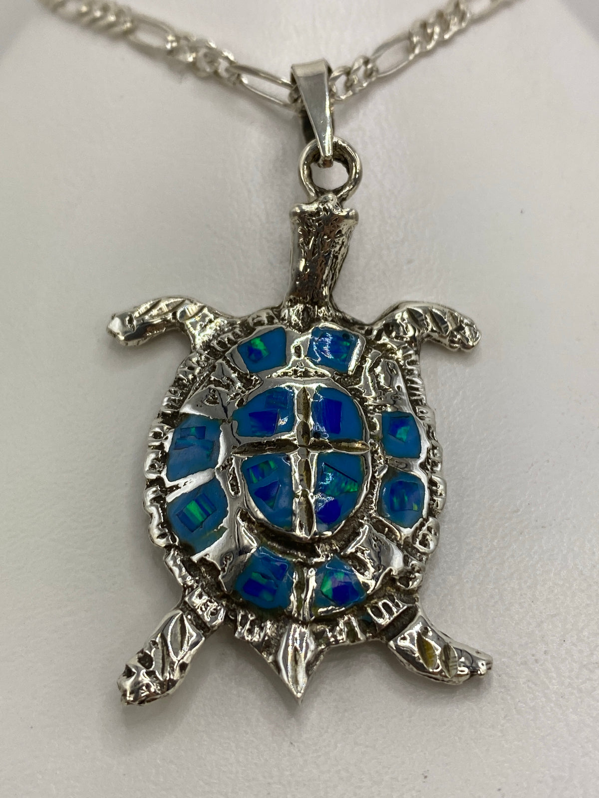 Detalle frontal del dije tortuga mostrando el ópalo azul en cada segmento