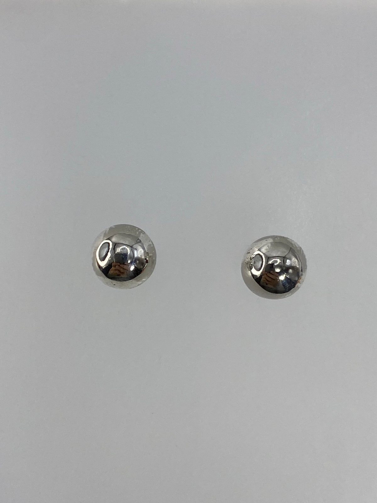 Detalle de los aretes mostrando el acabado pulido y reflejante de la plata