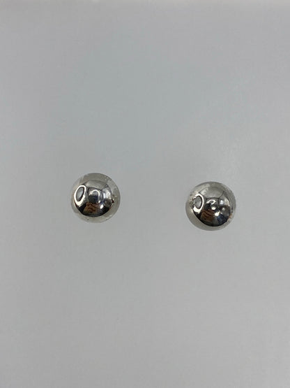 Detalle de los aretes mostrando el acabado pulido y reflejante de la plata