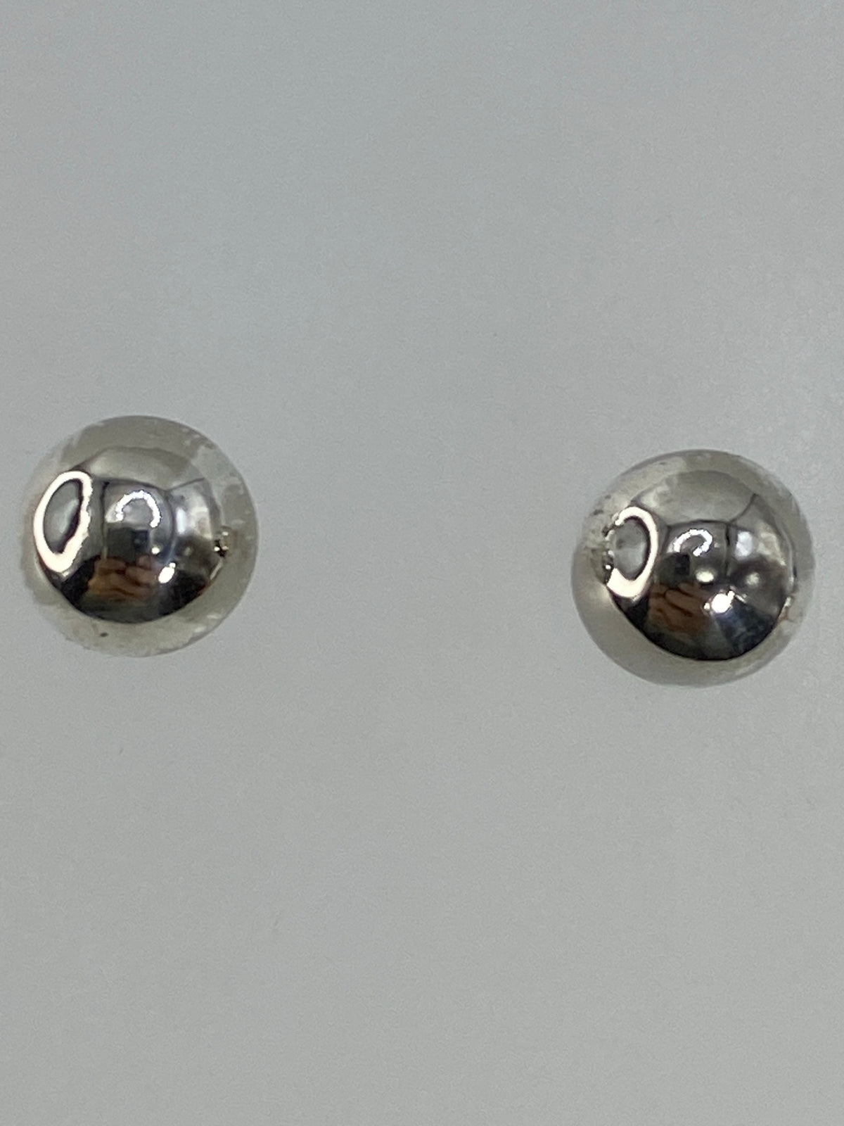 Aretes sobre fondo blanco con cierre de poste y tuerca visible