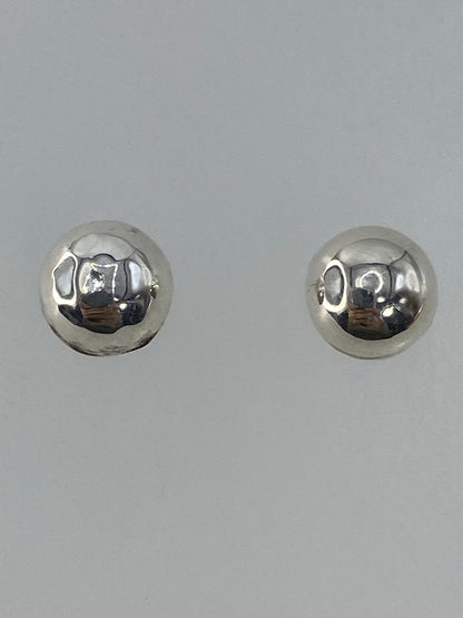 Aretes cartoneados sostenidos en la mano mostrando su tamaño y brillo