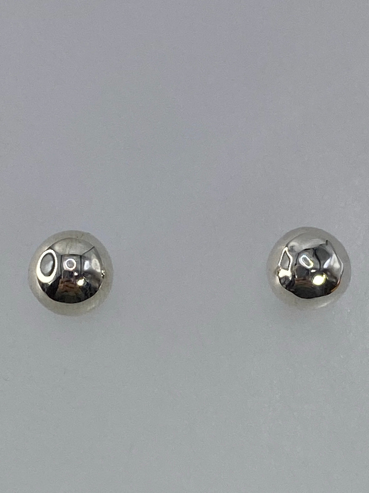 Aretes de plata en la mano mostrando su tamaño compacto de 1.5 cm