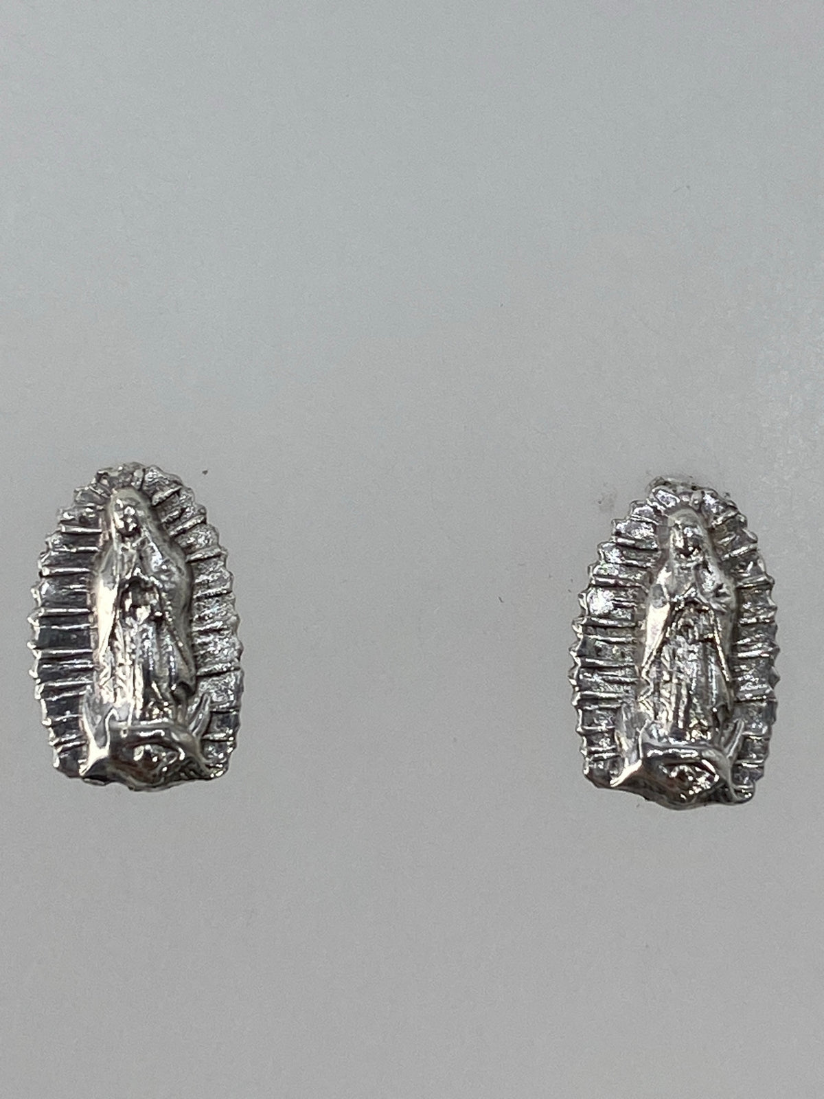 Detalle de los aretes religiosos en plata, cierre de poste