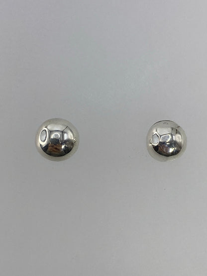 Par de aretes de plata cartoneado, esferas brillantes sobre fondo neutro