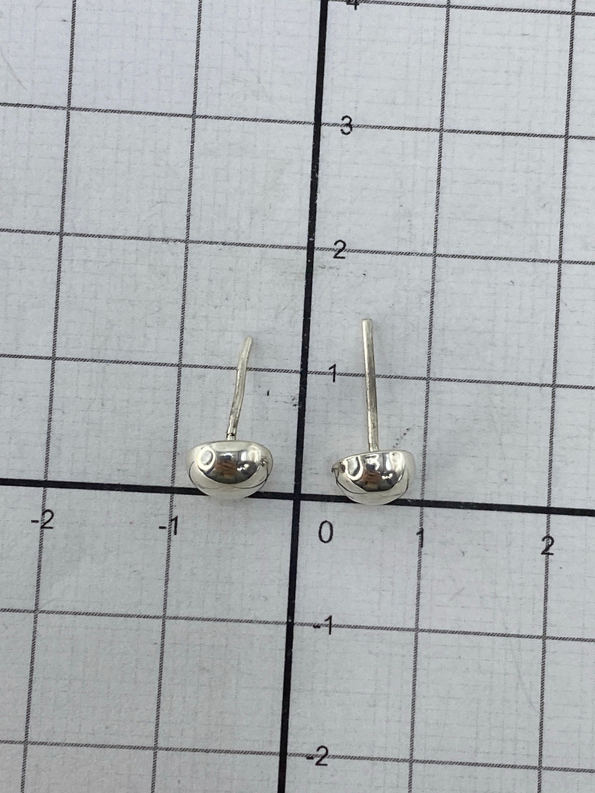 Aretes puestos en oreja, mostrando el largo de 1.5 cm y el cierre de poste