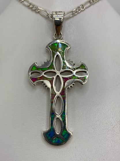 Dije cruz de plata con ópalo de fuego multicolor en tonos verde, púrpura y azul colgando de cadena plateada