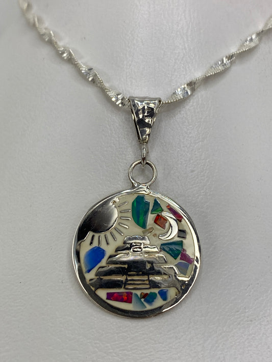 Dije de plata con ópalo de fuego multicolor y diseño prehispánico (sol, luna, pirámide) sobre fondo blanco