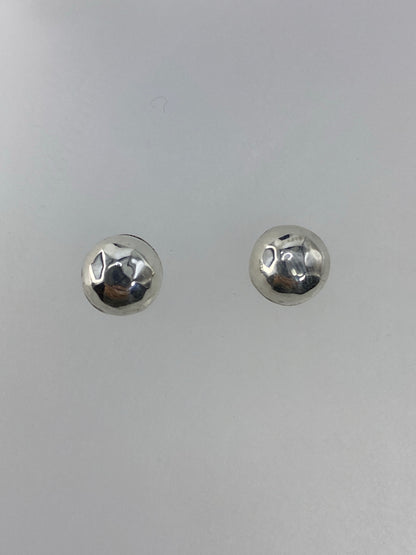 Detalle frontal de los aretes mostrando el acabado espejo del cartoneado