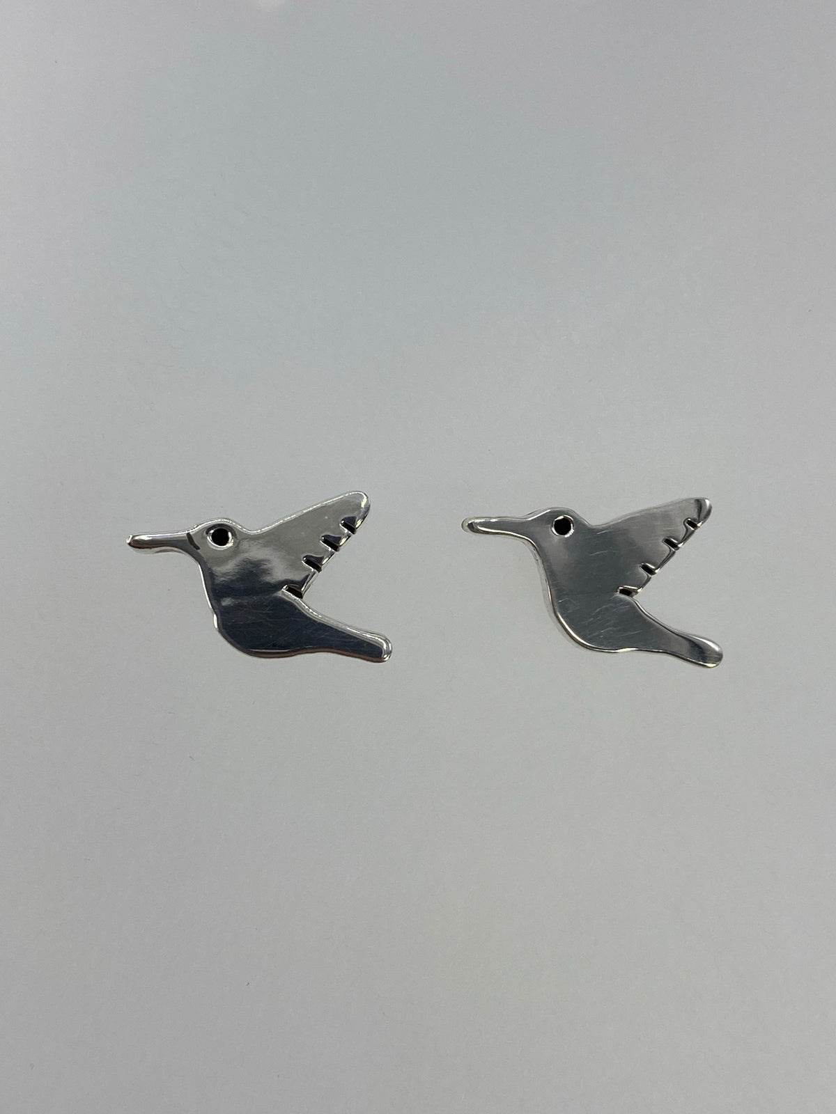 Detalle frontal de un arete colibrí en plata 925 mostrando el trabajo artesanal de cartoneado