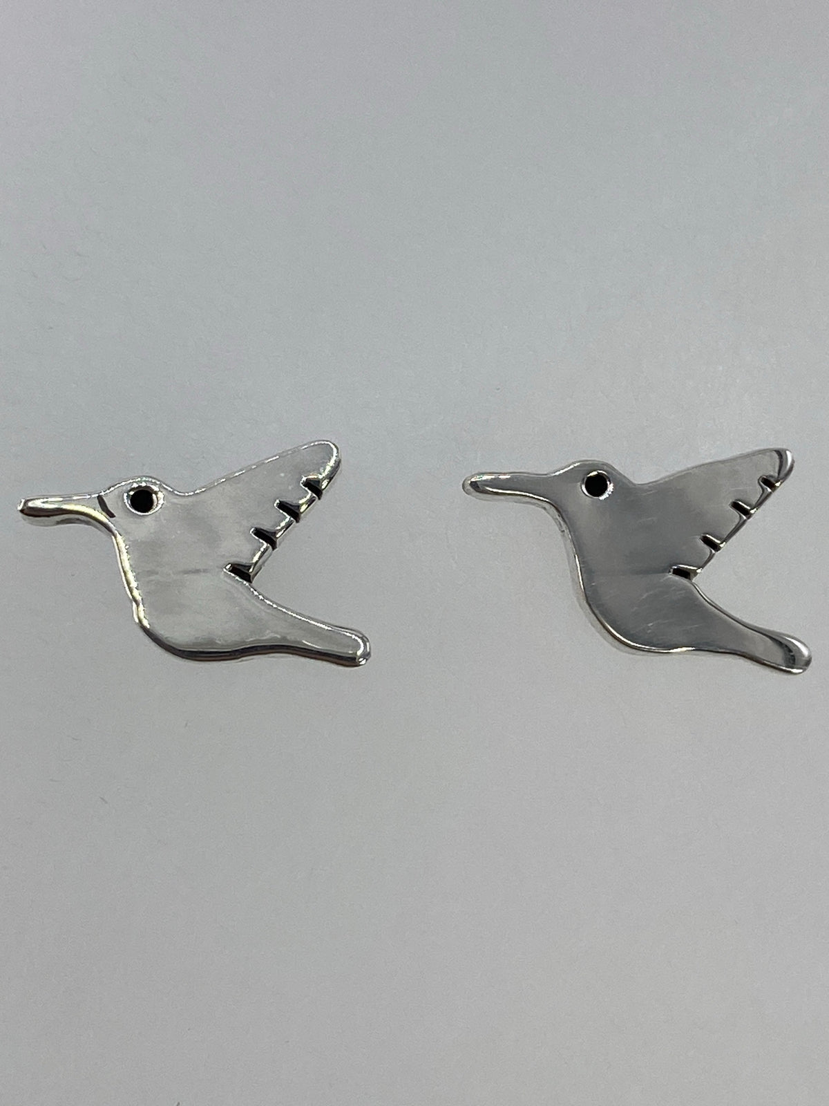 Vista lateral del arete colibrí de plata, viendo el volumen y profundidad del cartoneado