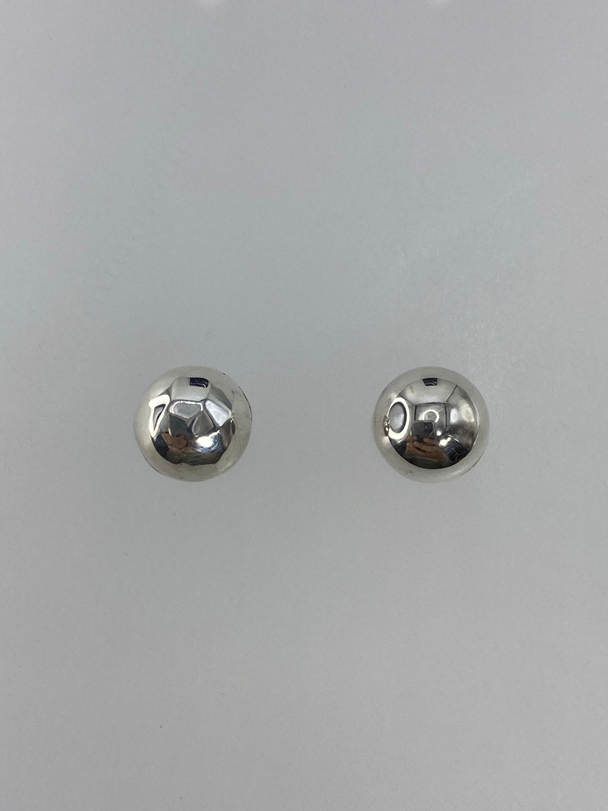 Detalle de los aretes de plata 925 mostrando el acabado pulido y el Quinto