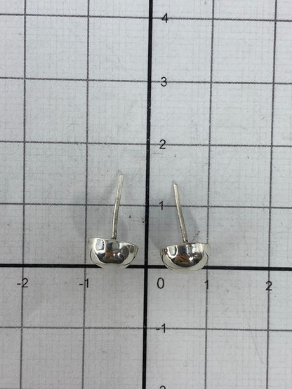 Aretes minimalistas en la mano, demostrando su tamaño compacto de 1.2 cm