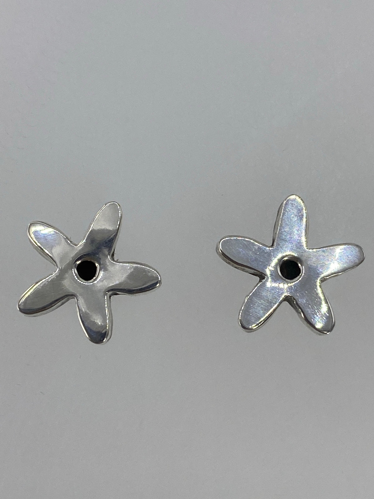 Aretes de plata 925 colocados sobre una regla mostrando 1.5 cm de largo