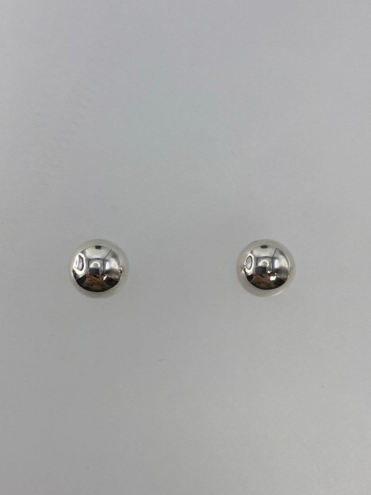 Detalle de los aretes de cartoneado mostrando la precisión de la esfera de plata 925