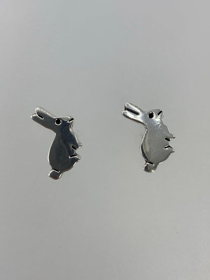 Aretes minimalistas de plata cartoneado en forma geométrica sobre fondo neutro