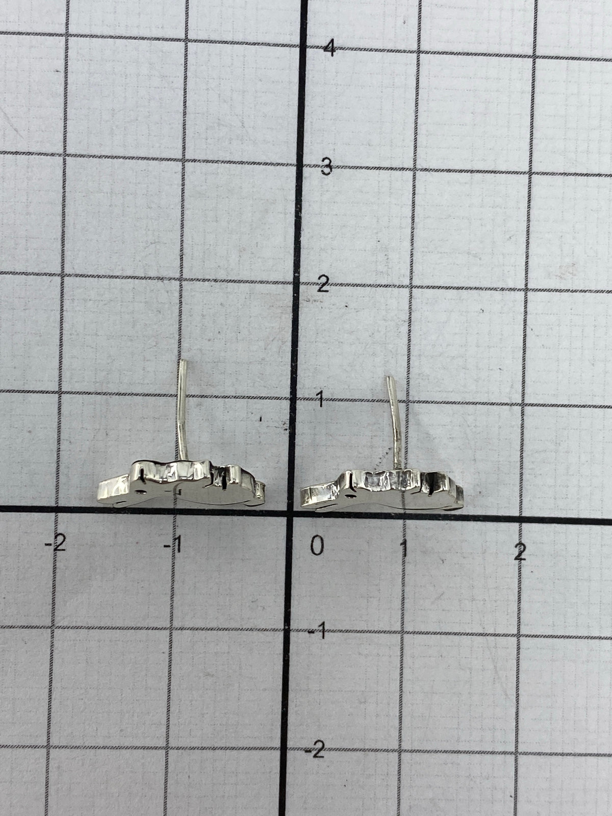 Aretes livianos de plata junto a regla de medidas mostrando 1.1 cm de largo