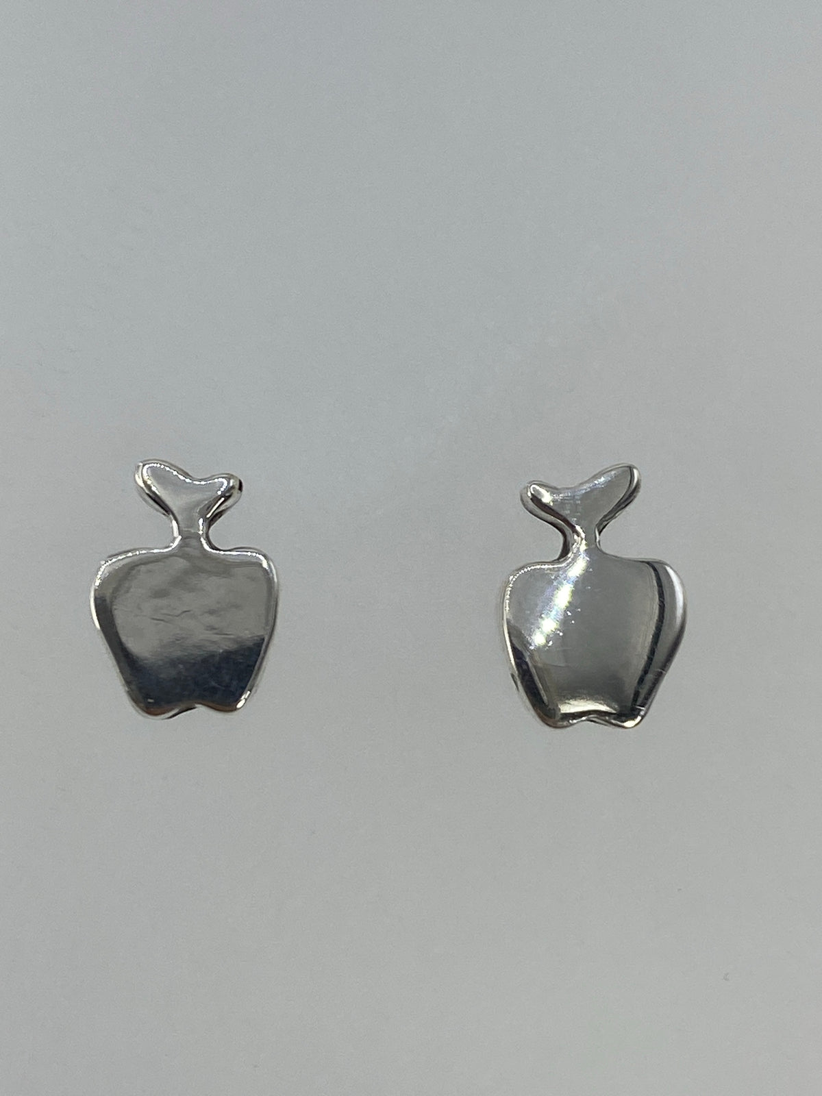 Par de aretes de plata cartoneado minimalista en forma de manzana, vista frontal