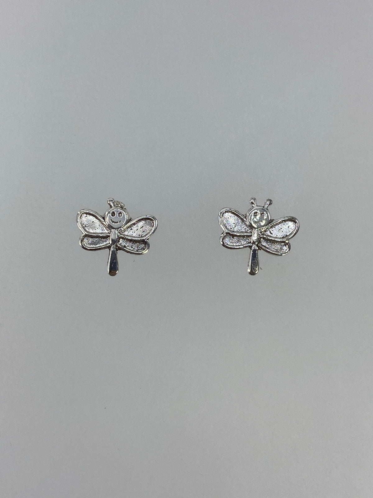 Detalle frontal de los aretes libélula mostrando las alas texturadas en cartoneado