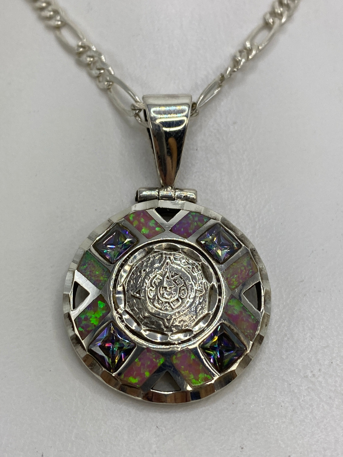 Dije circular de plata 950 con Ópalo de Fuego rosa en el centro, rodeado de granulado y triángulos negros