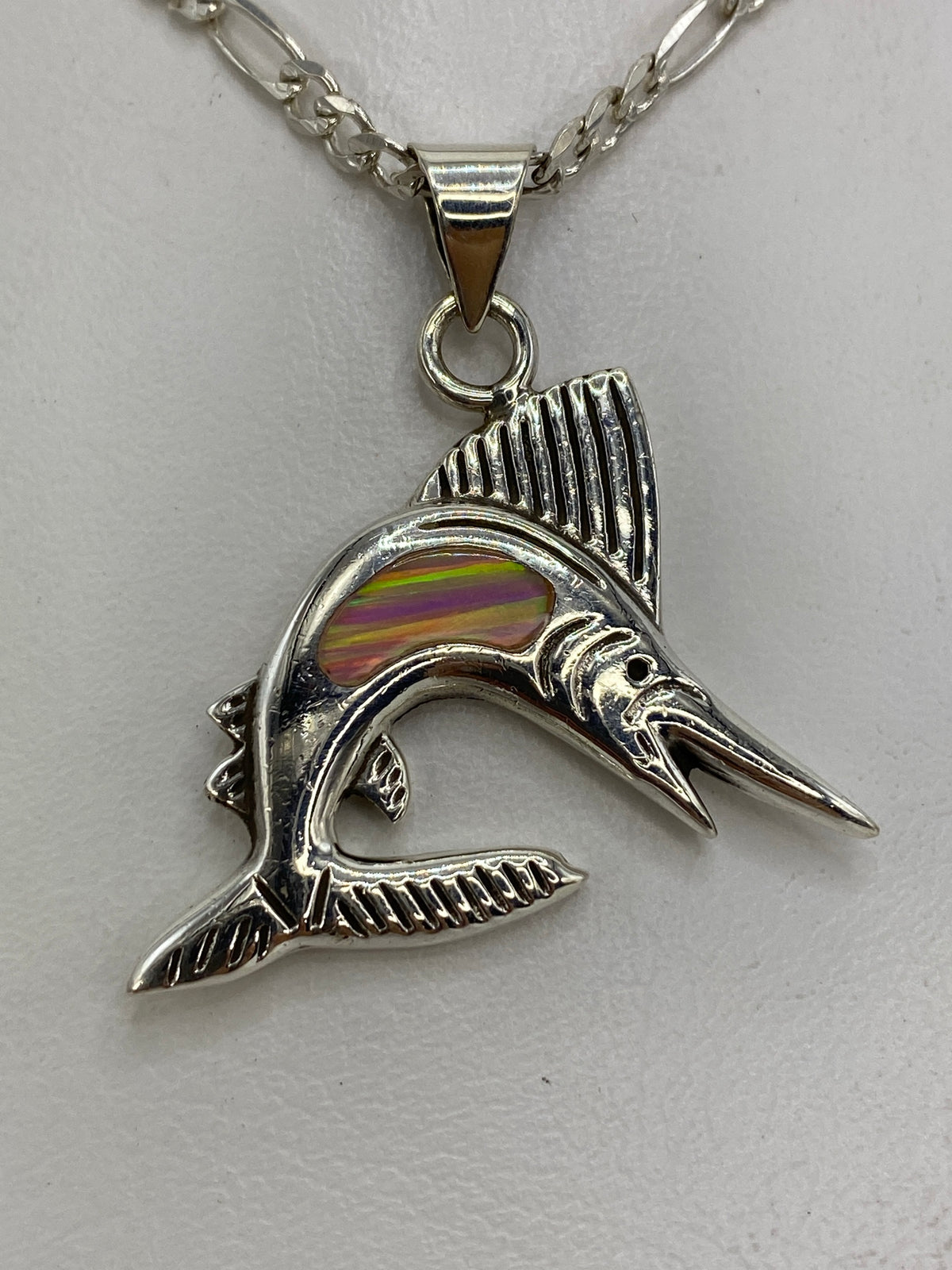 Dije de plata en forma de pez saltarín con ópalo de fuego rosa, colgado en cadena sobre fondo blanco