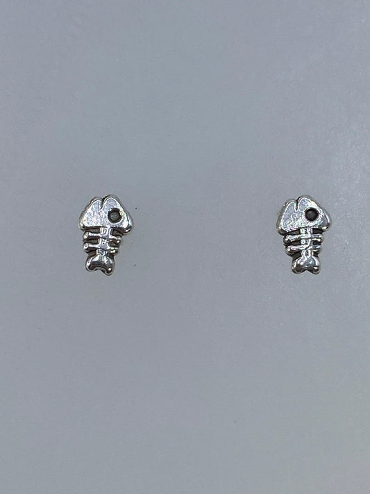 Aretes de plata cartoneado en forma de espina de pez, minimalistas y elegantes, posados en plano