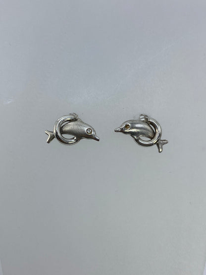 Detalle de los aretes delfín minimalistas en plata pulida