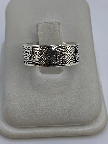 Anillo de plata con motivos geométricos prehispánicos en la mano