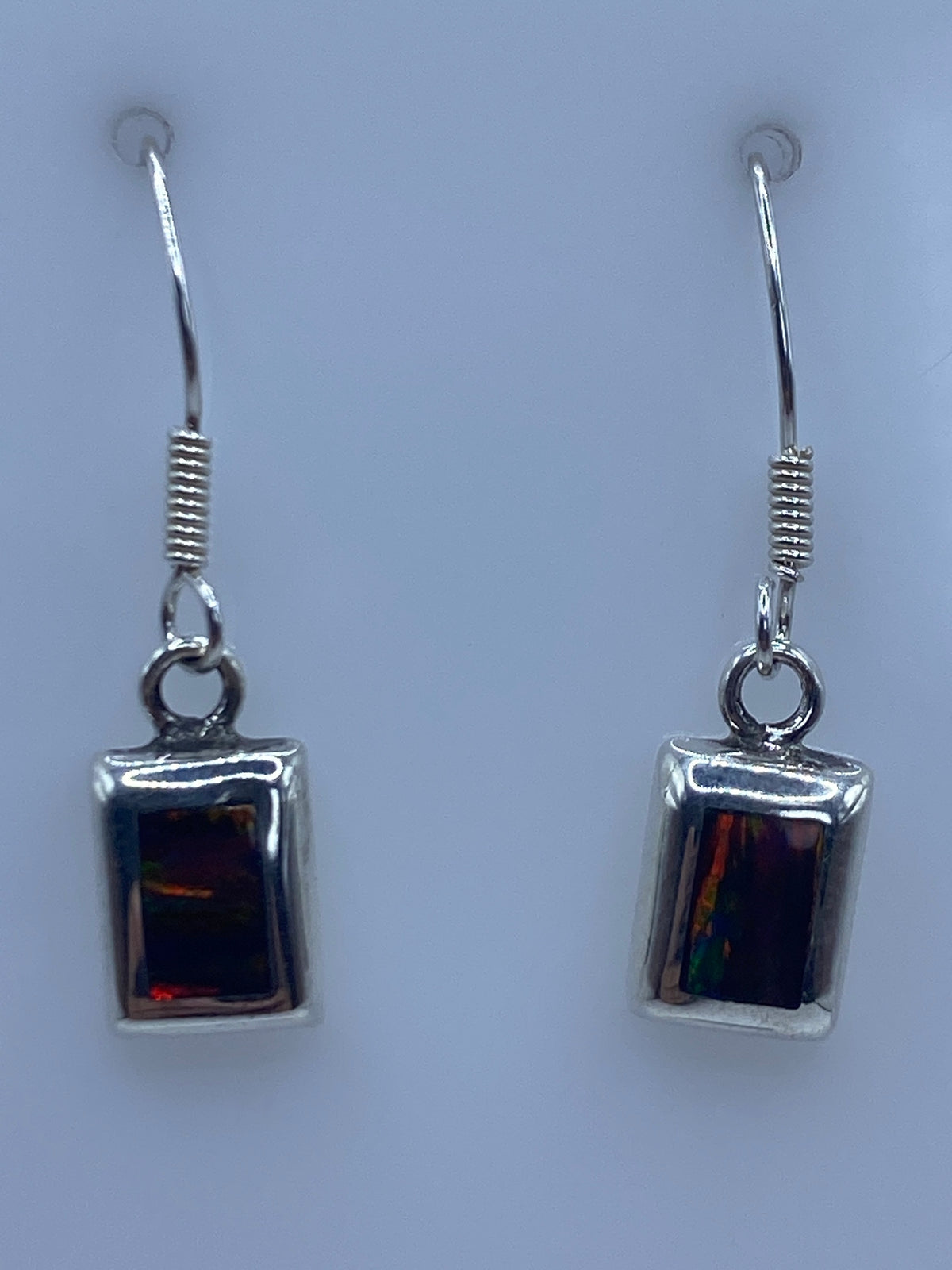 Par de aretes de plata 925 con Ópalo de Fuego multicolor, colgando sobre fondo azul