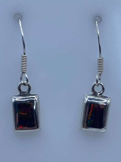 Par de aretes de plata 925 con Ópalo de Fuego multicolor, colgando sobre fondo azul