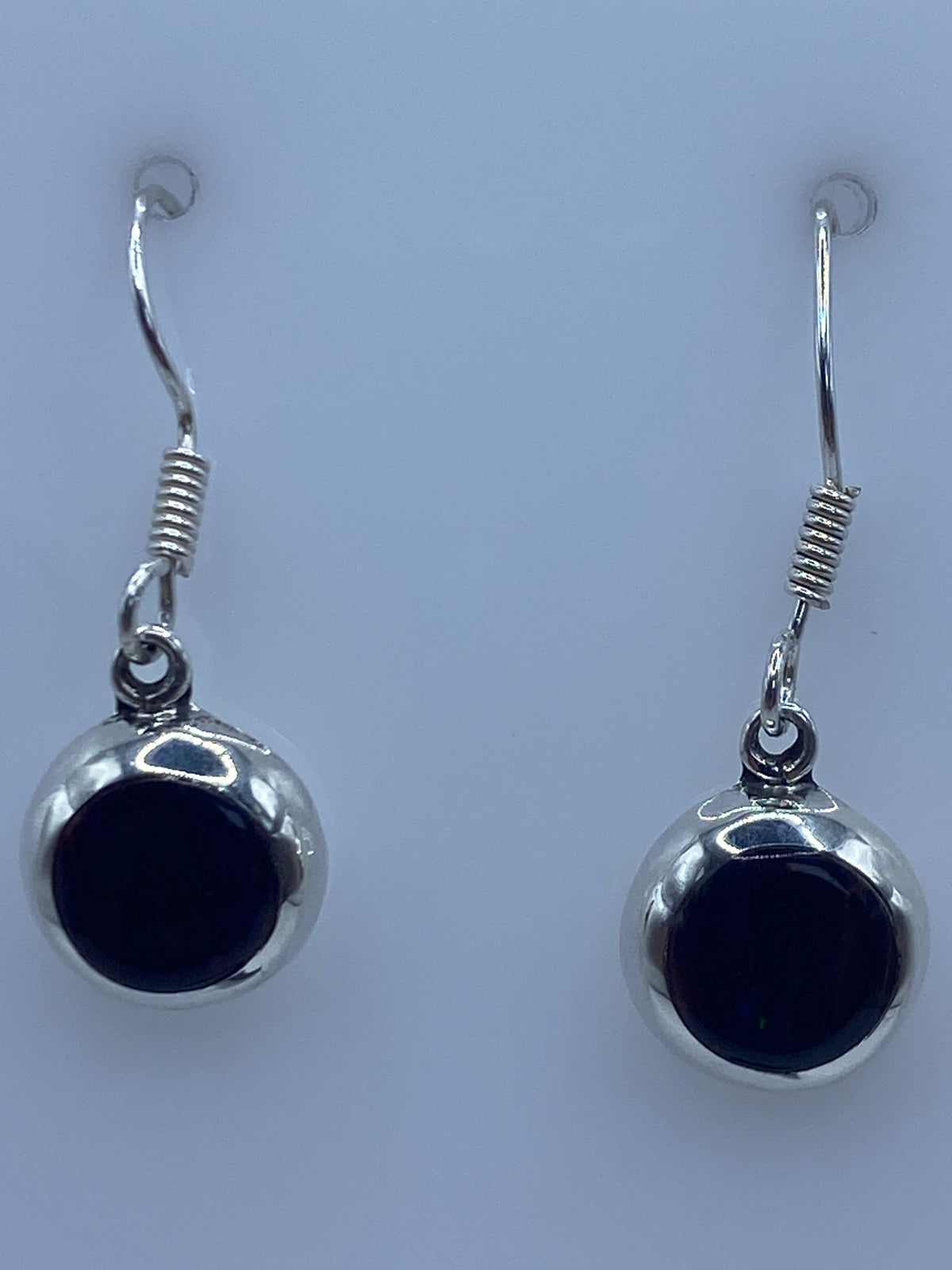Aretes en la mano mostrando el tamaño delicado de 2.7 cm y el Quinto 925