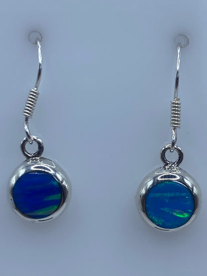 Aretes en la palma de la mano mostrando el tamaño delicado y el tono azul del Ópalo