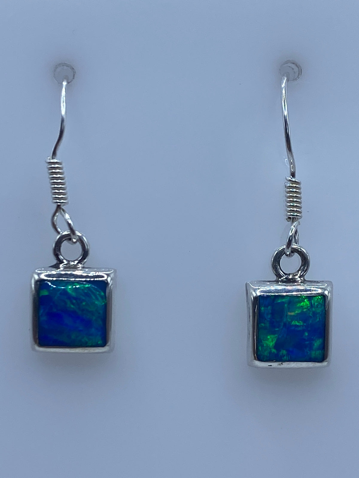 Par de aretes de plata 950 con ópalo de fuego azul, vistos de frente