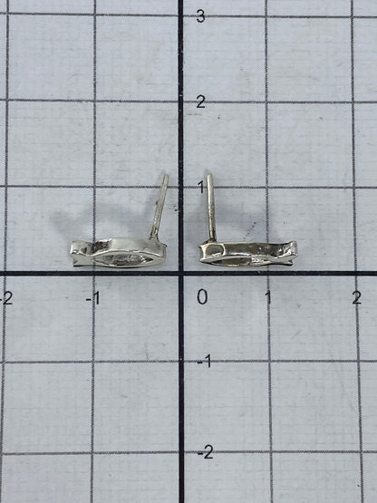 Aretes de plata pez colocados sobre una regla milimetrada, mostrando su escala
