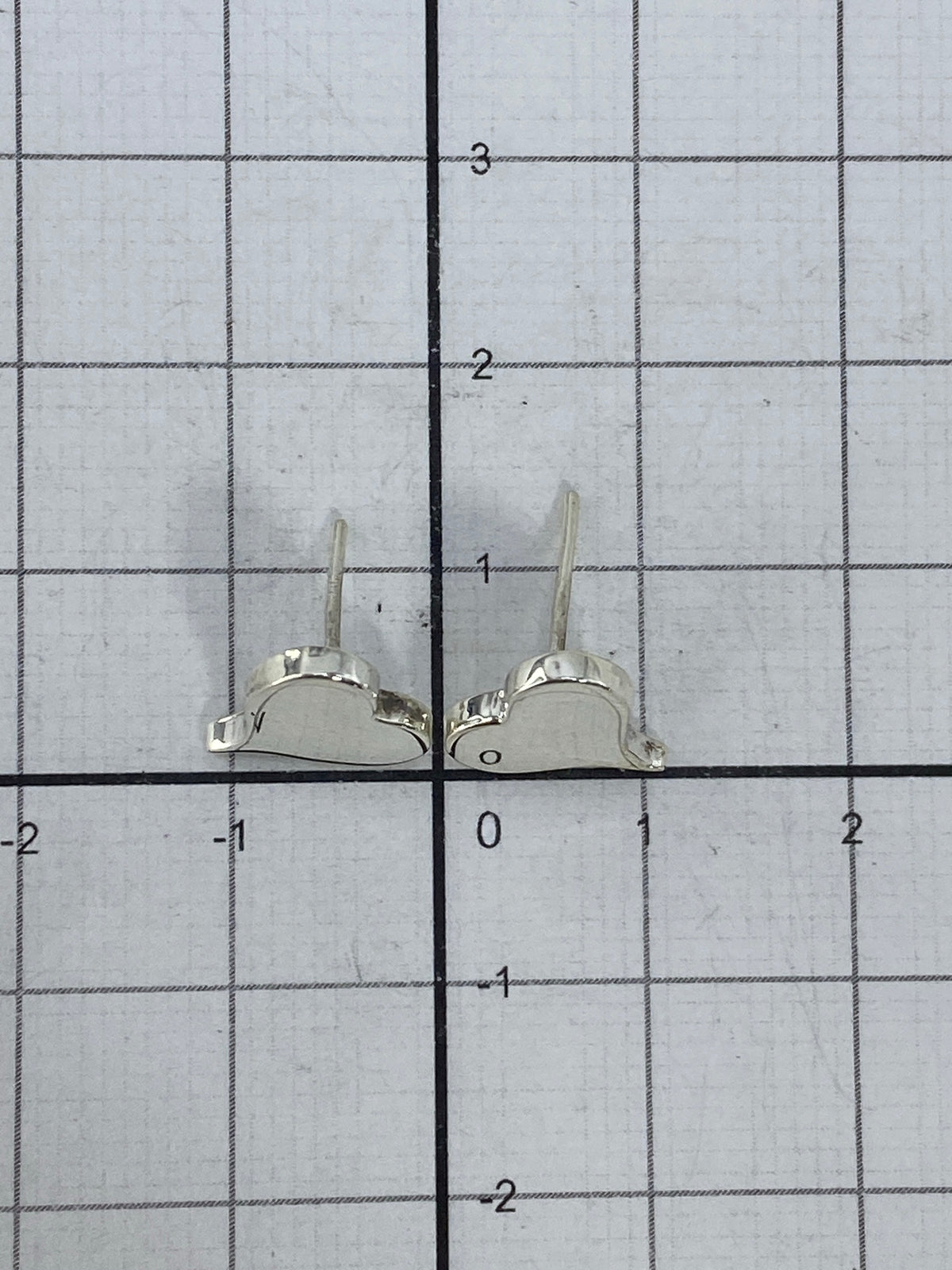 Aretes sobre balanza mostrando su peso ligero de 0.9 g