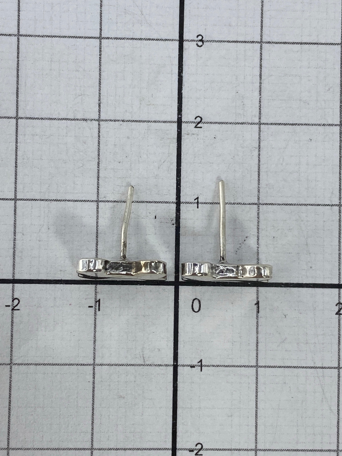 Aretes pequeños de plata 925 sobre fondo blanco mostrando su ligereza